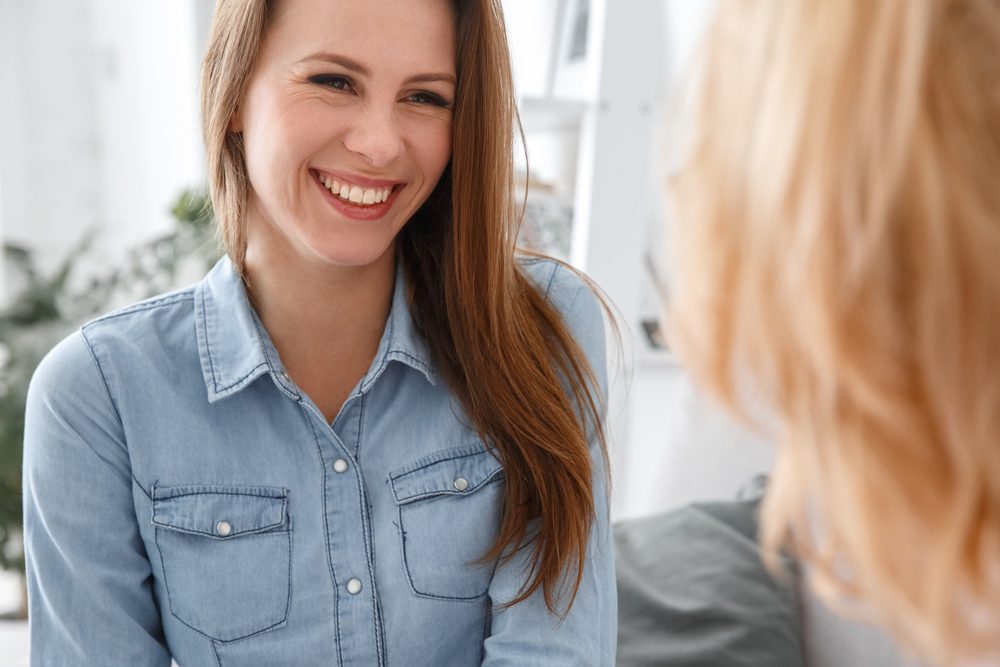 Female psychologist therapy session with client indoors sitting patient smiling cheerful close-up.