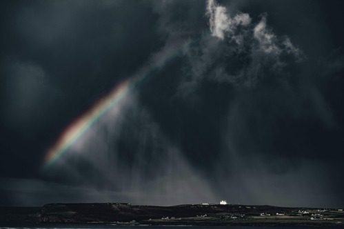 a storm with a rainbow through the clouds